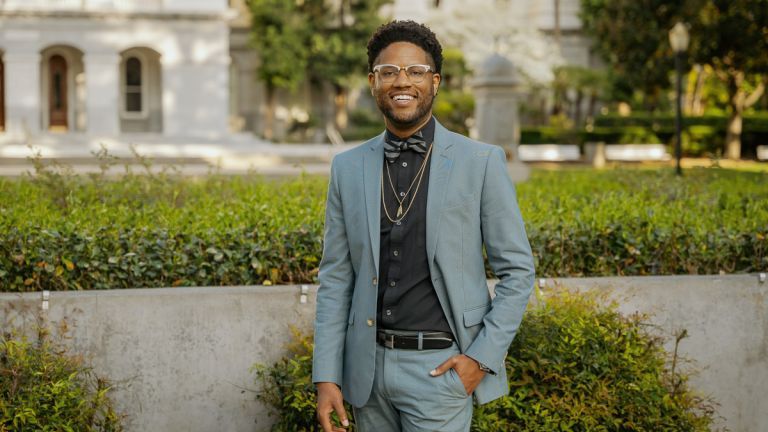 A man wearing a suit puts his right hand in his front pocket