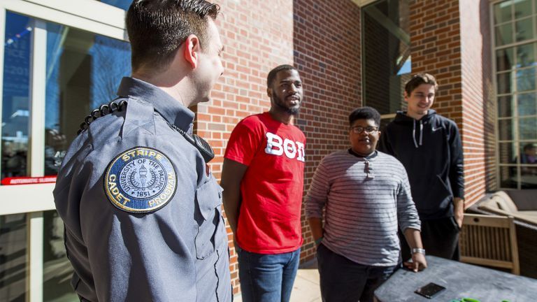 a STRIPE escort talks to three students