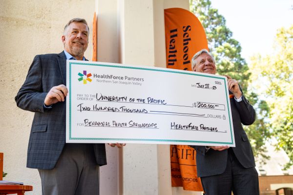 two men hold a large check