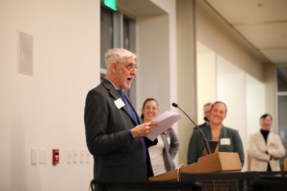 A man speaks into a microphone at an event indoors