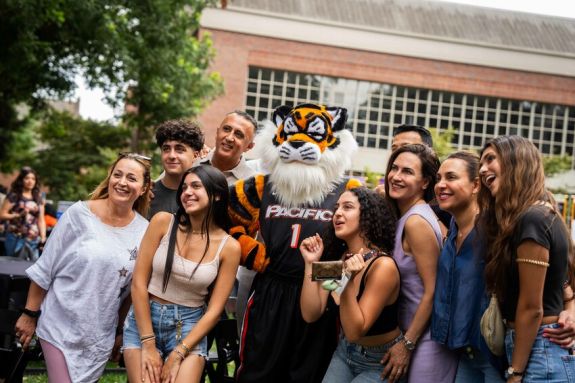 A group of students huddled around Power Cat posing for a picture.