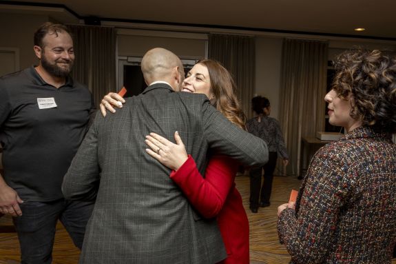 A male and female exchange a hug during an event. 