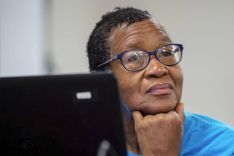 a woman with a laptop in front of her looks thoughtful