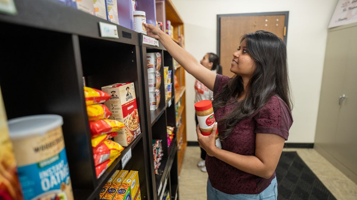 A student stocks shelves at the Pacific Food Pantry.