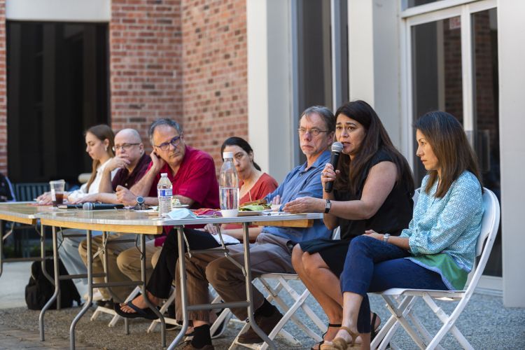 A student and faculty members sit at a long table for a panel discussion.