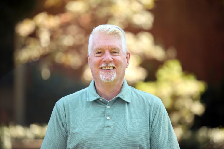 A close up photo of a man in a teal polo shirt