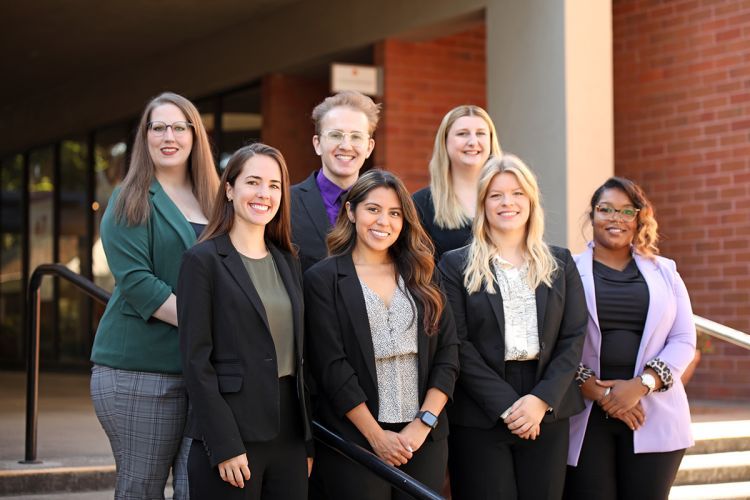 Seven students pose on a staircase for a photo