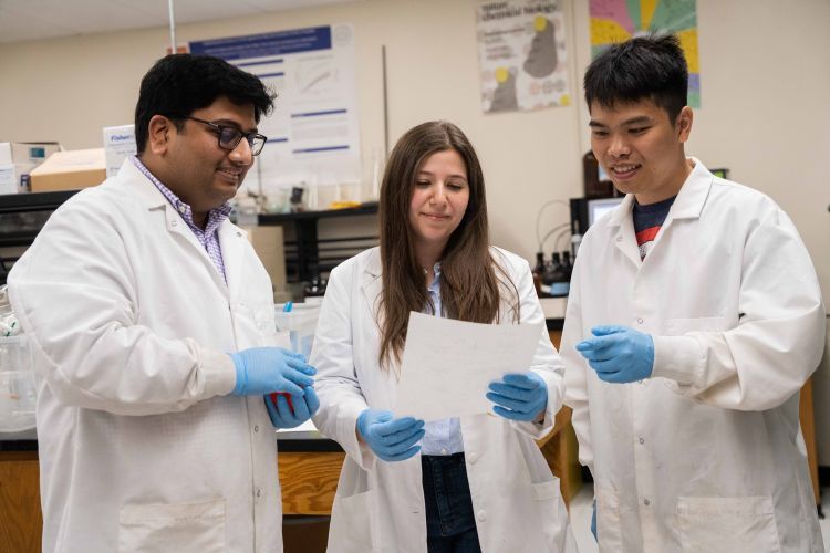 three students in white lab coat