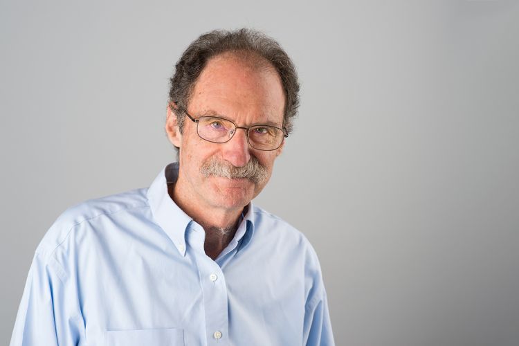 A man in a button down shirt smiles for a photo