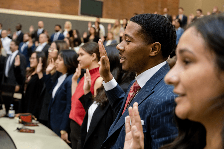 A group of students take an oath and hold up their right hand