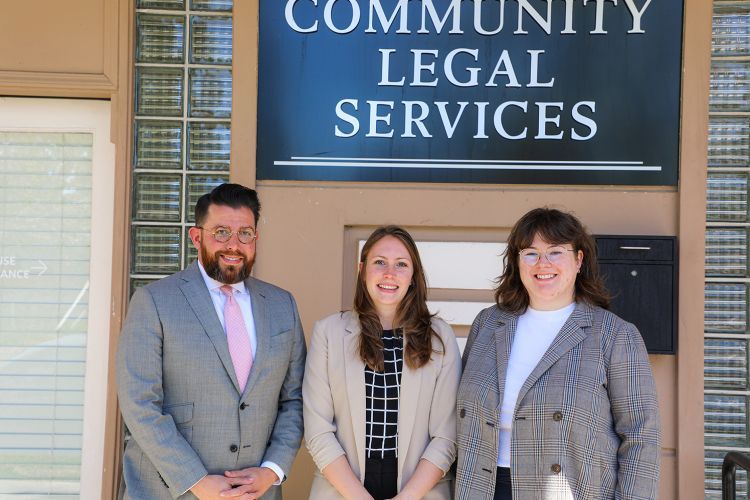 Three people pose for a photo outside of a building.