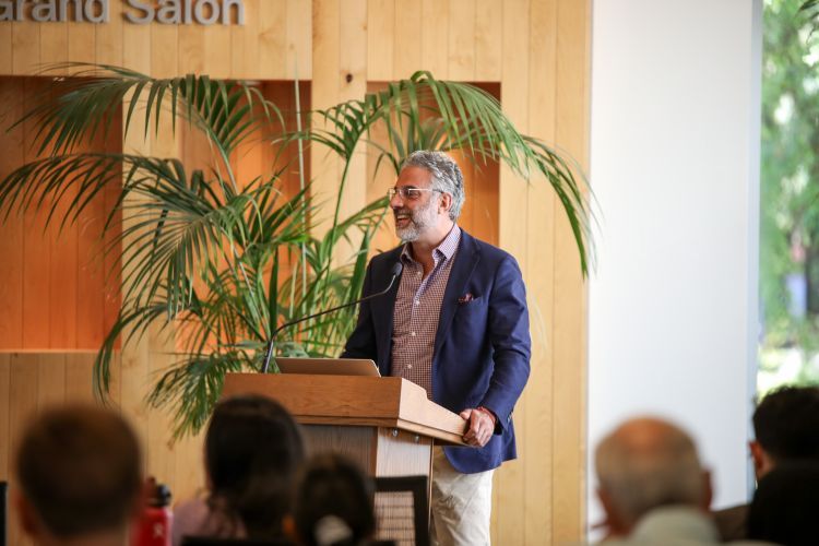 A male professor at a podium speaks to a crowd