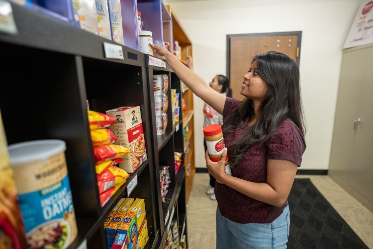 A student stocks shelves at the Pacific Food Pantry.