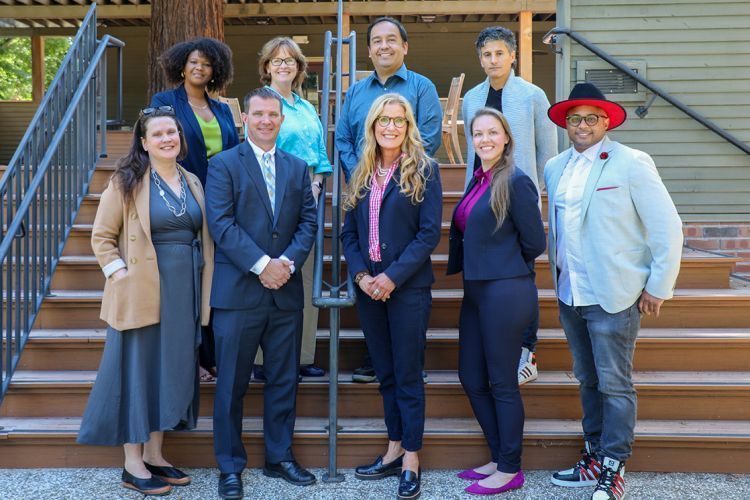 Nine professors pose for a photo outdoors