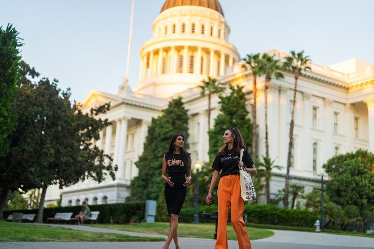 Two girls walk in front of the California State Capitol Building