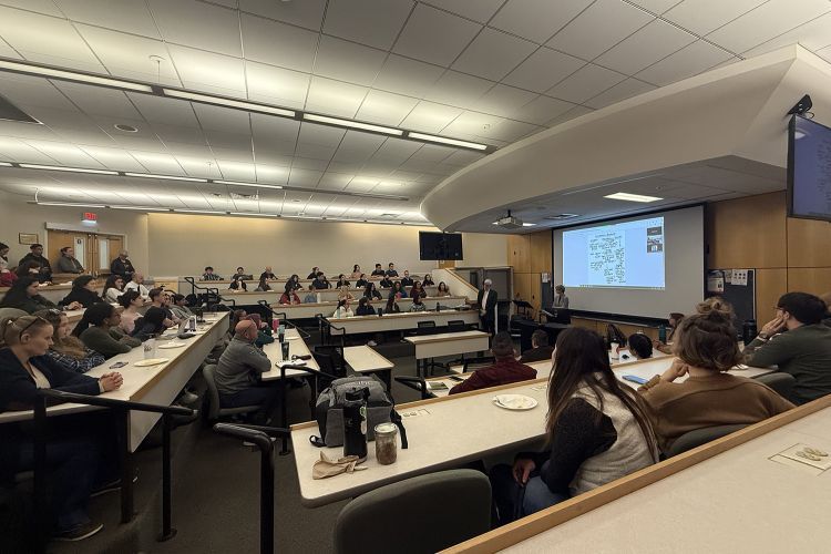 A classroom full of people listen to a presentation