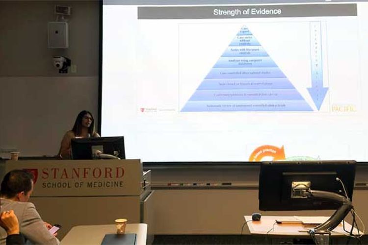 slide that reads Strength of Evidence during a presentation on a bright screen in a darkened lecture room with a person at the podiumm to the left of the screen