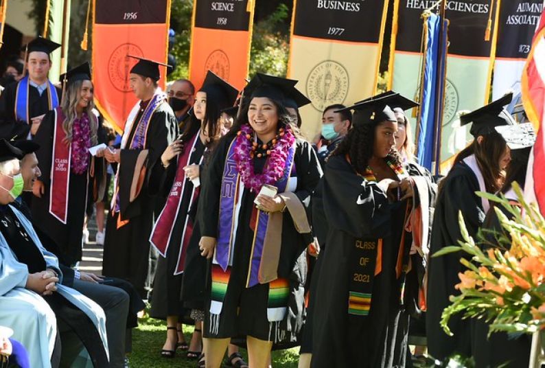 Pacific graduates walking past school and college banners