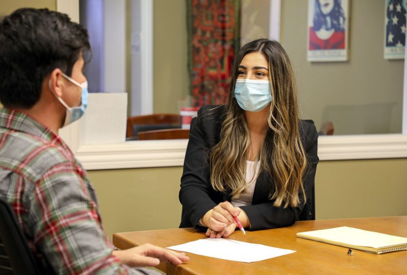 Third-year law student Flora Feizi looks at a client while conducting a meeting in the school's legal clinics. Both individuals are seated. 