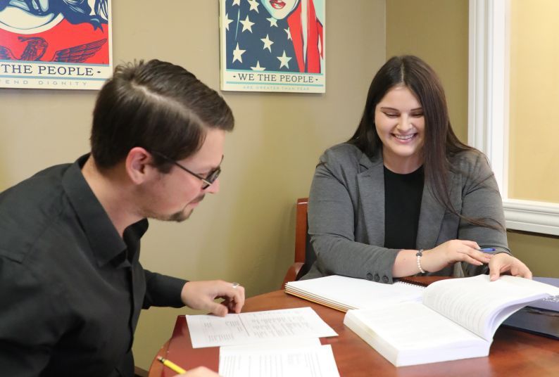 Two students look at books while seated