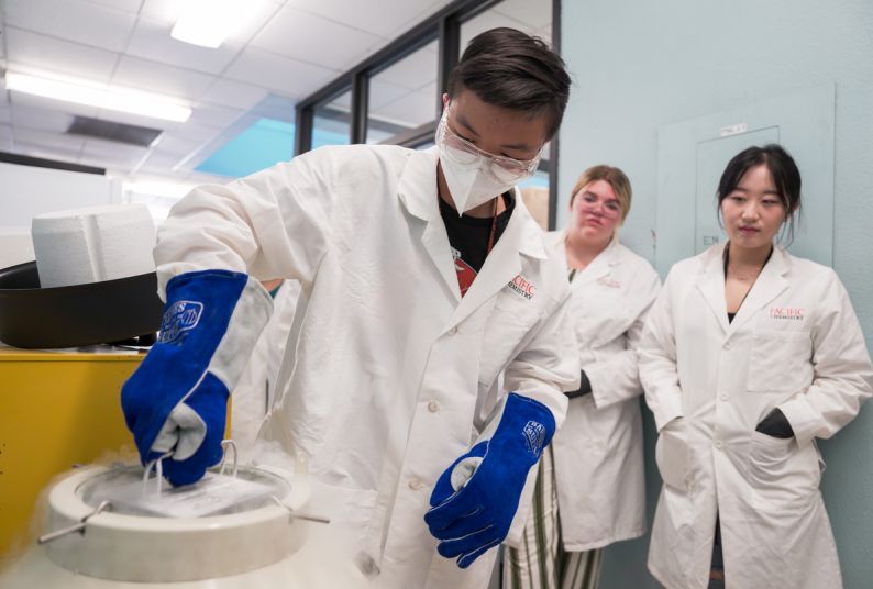 three students in white lab coats