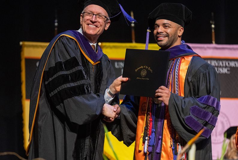 A student and law dean pose on graduation.