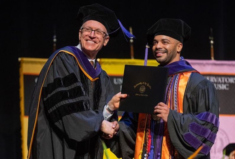 Dean Schwartz presents a diploma to a law school graduate