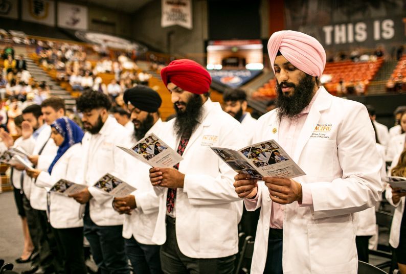 Students in white coats reading programs.