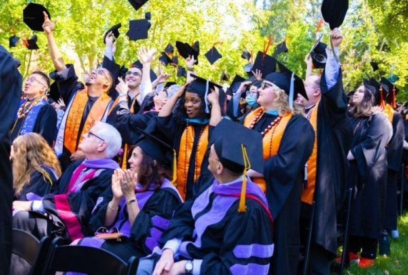 Graduate throw their caps in the air.