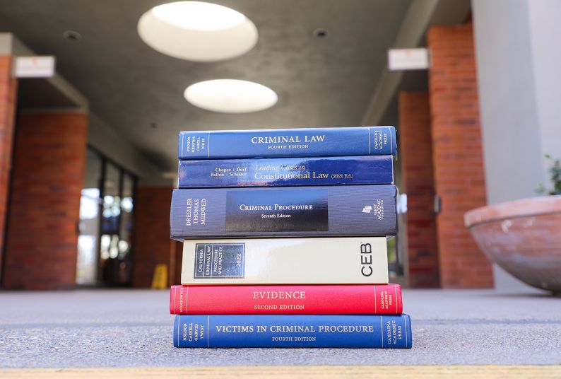 A pile of textbooks sit on the ground outside.