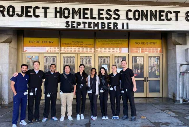 Group of student volunteers in front of Bill Graham Civic Auditorium under a marquee reading Project Homeless Connect 82