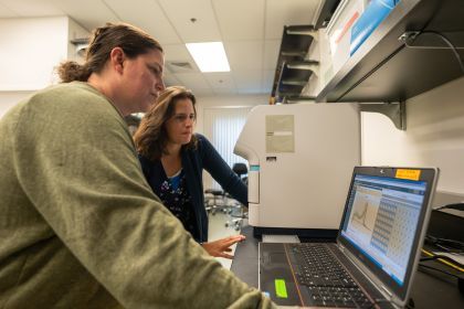 Two professors standing in a lab looking at a computer