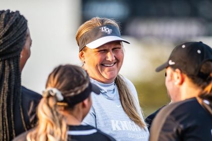 Cindy Ball-Malone smiles as she talks to three softball players