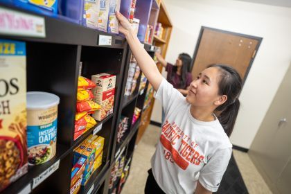 A student restocks shelves at the Pacific Food Pantry