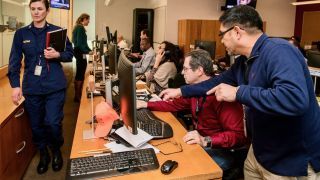 An emergency response team is shown working at their computer monitors.