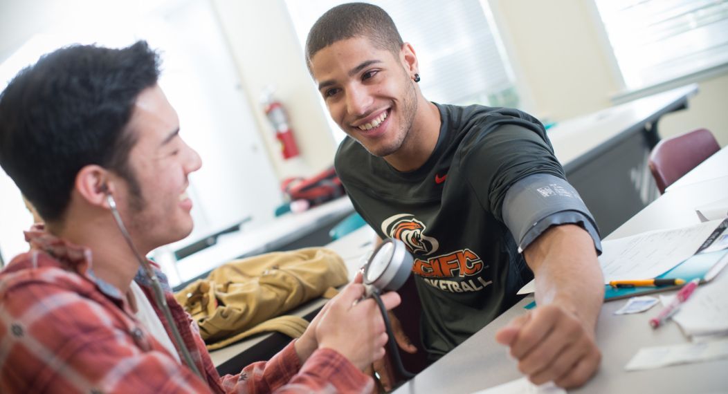 student using stethoscope on athlete