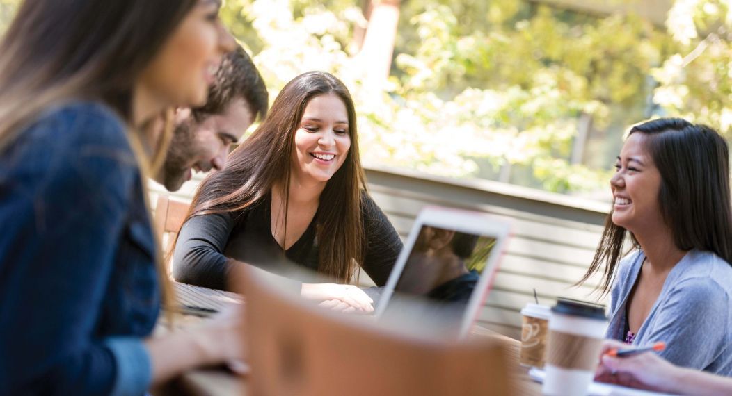 students sitting on Sacramento campus looking at laptops