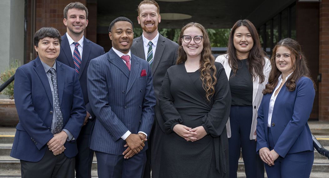 A group of about 8 students pose on the steps of a staircase outdoors