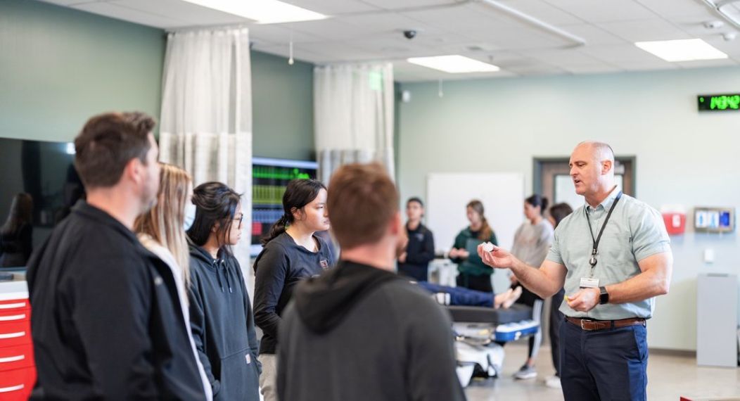 Photo shows Dr. Grant speaking with several students in the lab.