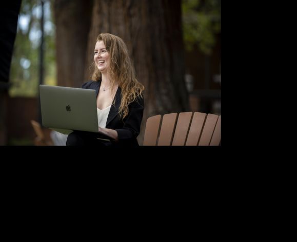 student with laptop sitting on chair outside