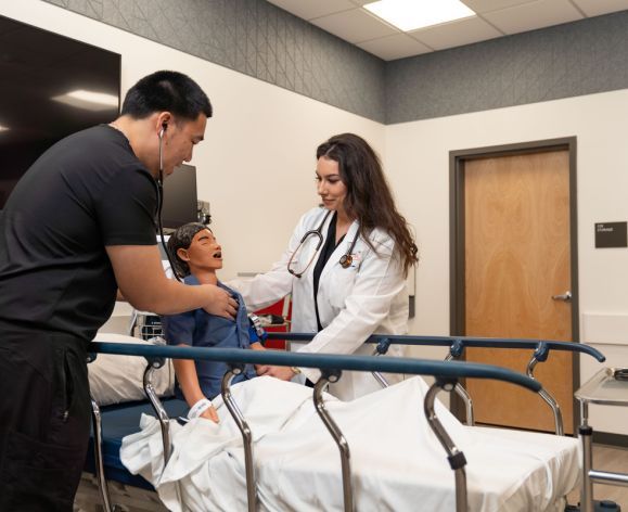 Photo shows two nursing students at Pacific's School of Health Science working with a manikin. 