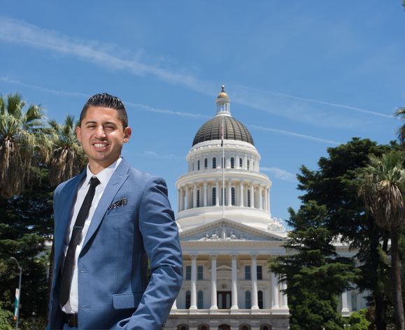 A law student poses in front of the capitol building.