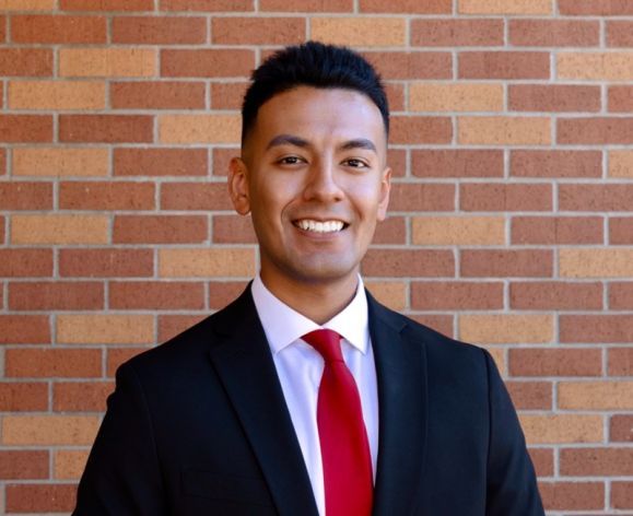 A portrait of a man wearing a suit in front of a brick wall