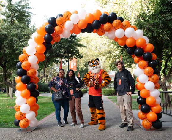 students and powercat under a balloon arch